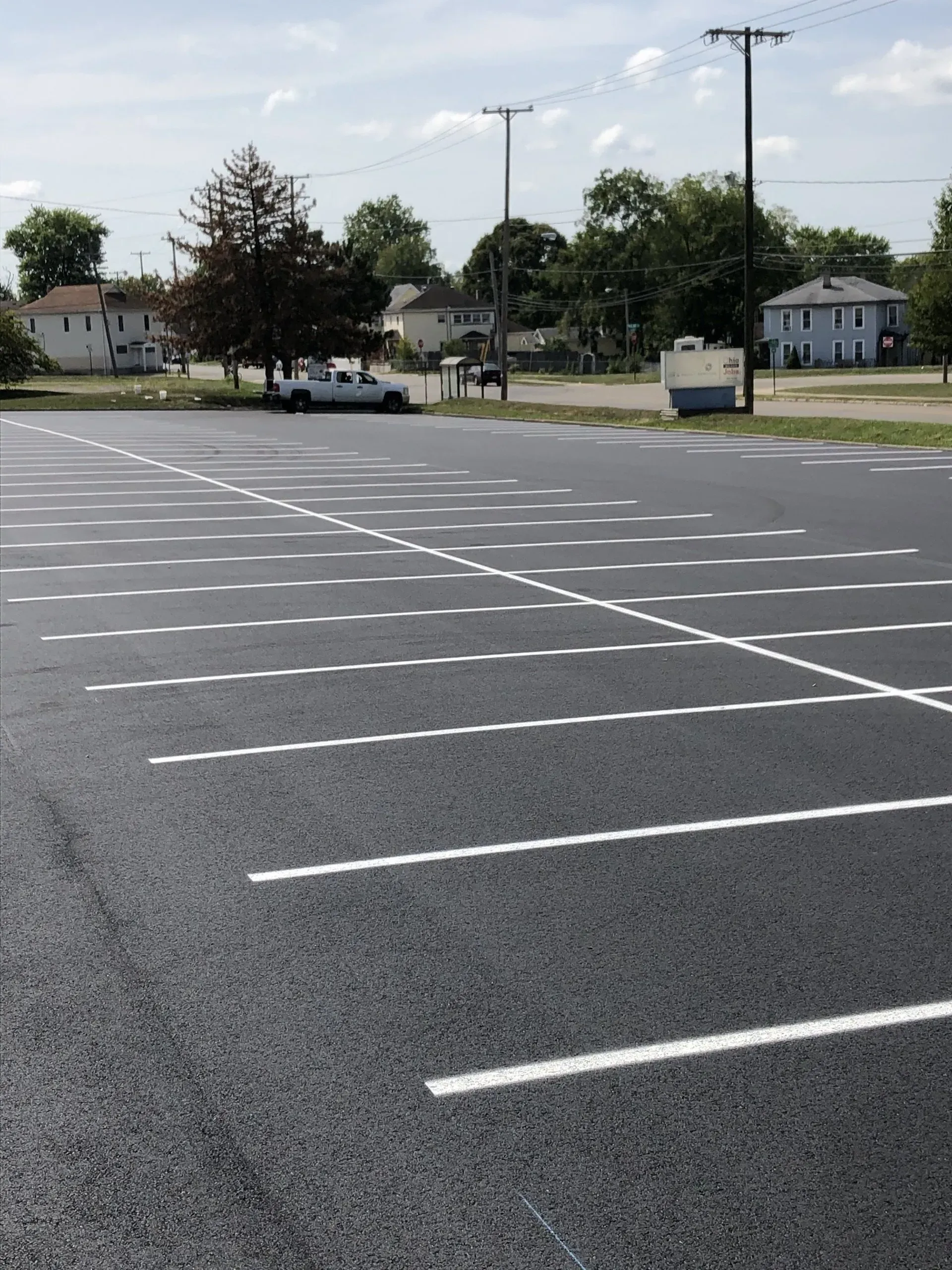 A newly paved parking lot with freshly painted white lines, seen from a low angle on a sunny day.