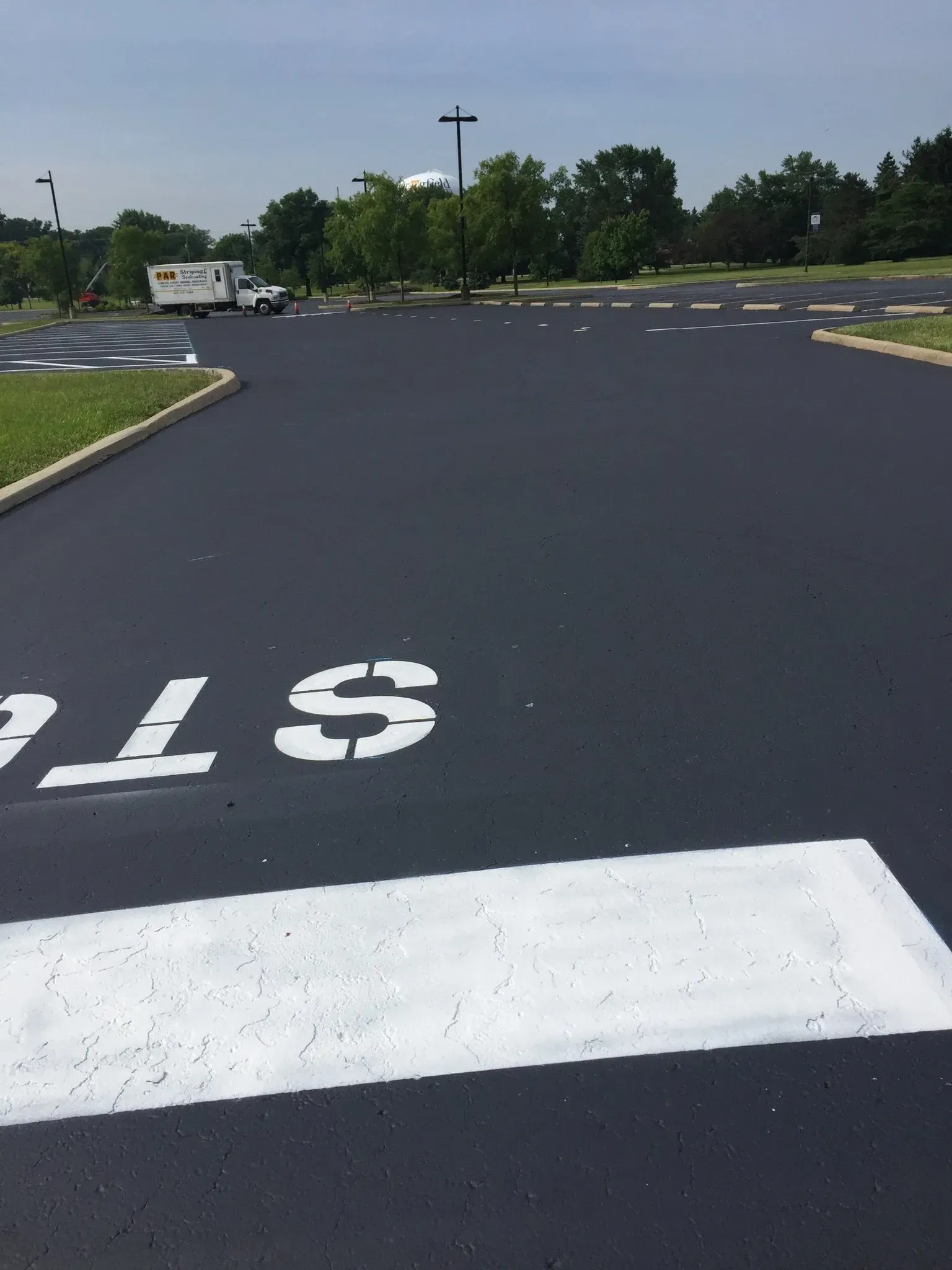 A freshly paved parking lot with a white stop bar and stenciled 