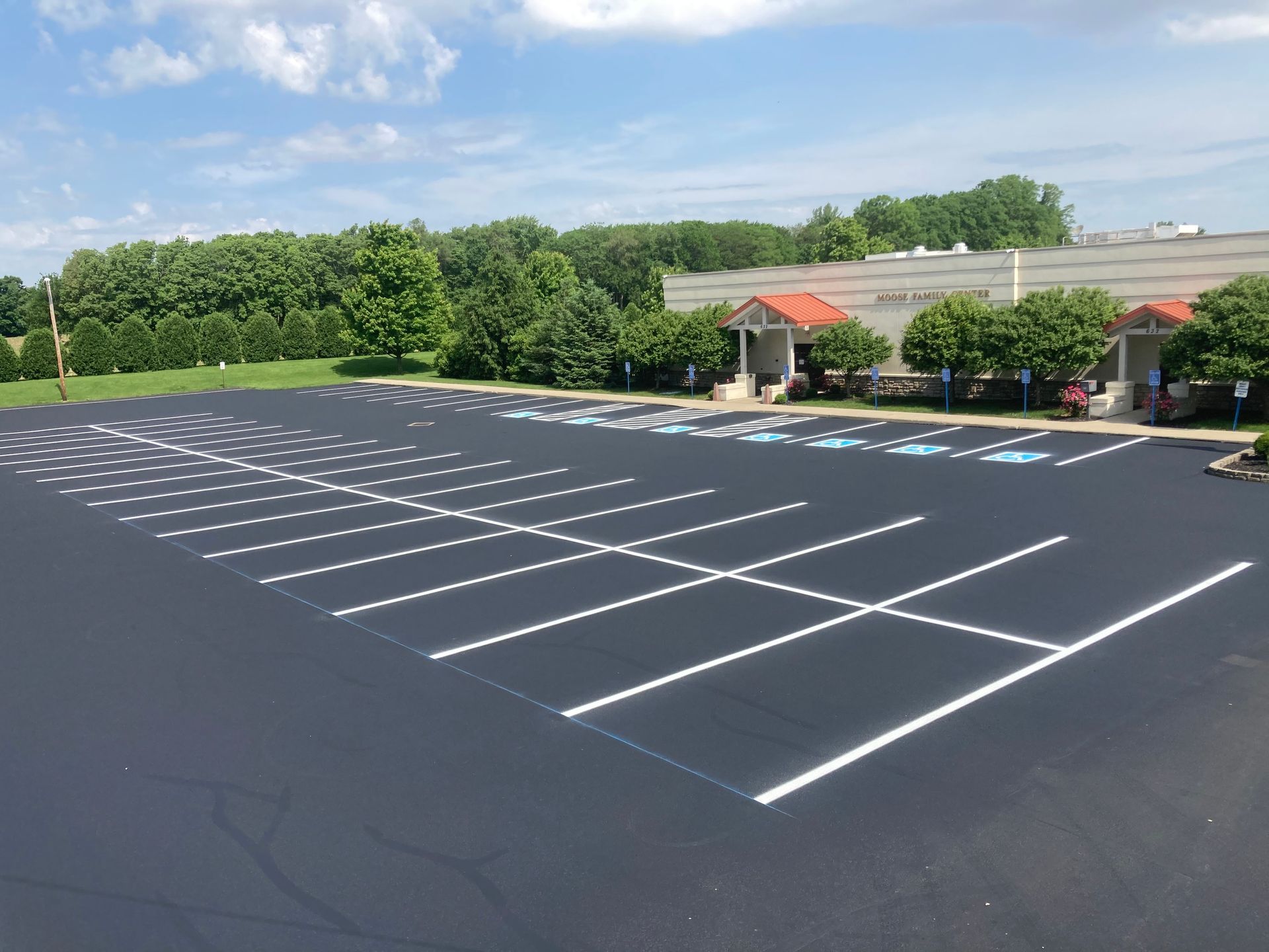 A freshly paved parking lot with white painted lines and designated handicap-accessible parking spaces.