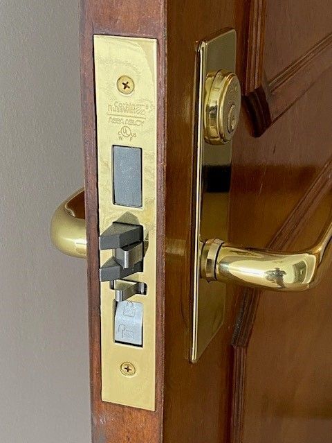 A man is fixing a door lock with a key.