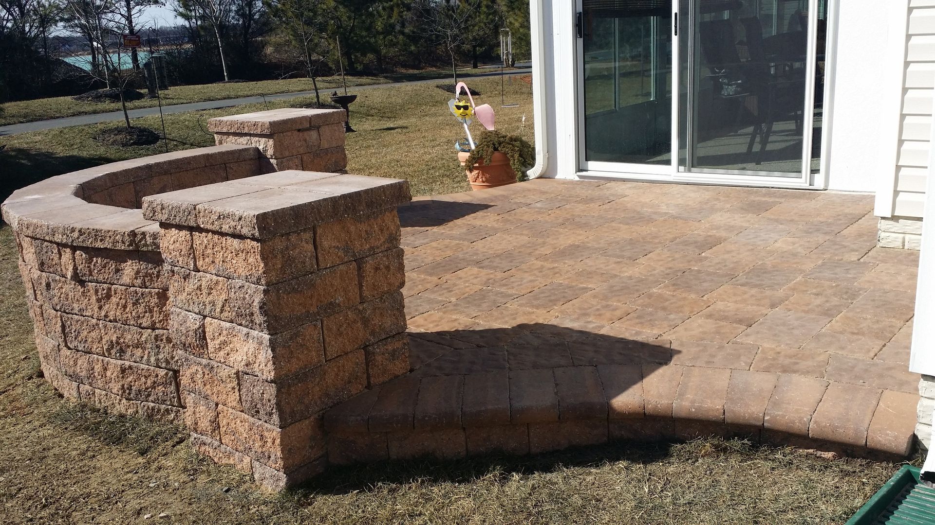 A patio with a stone wall and a sliding glass door