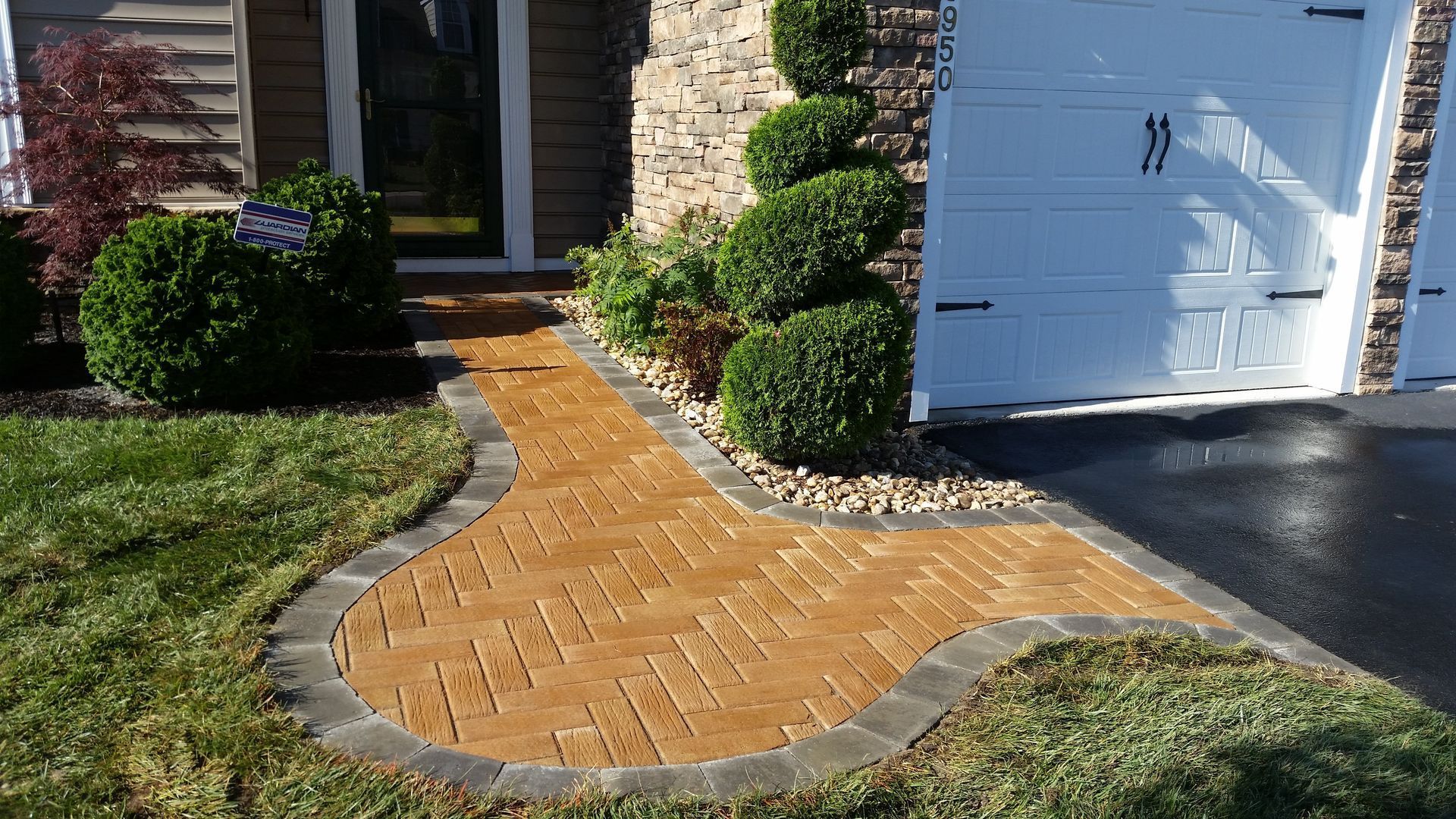 A brick walkway leading to a house with a white garage door.