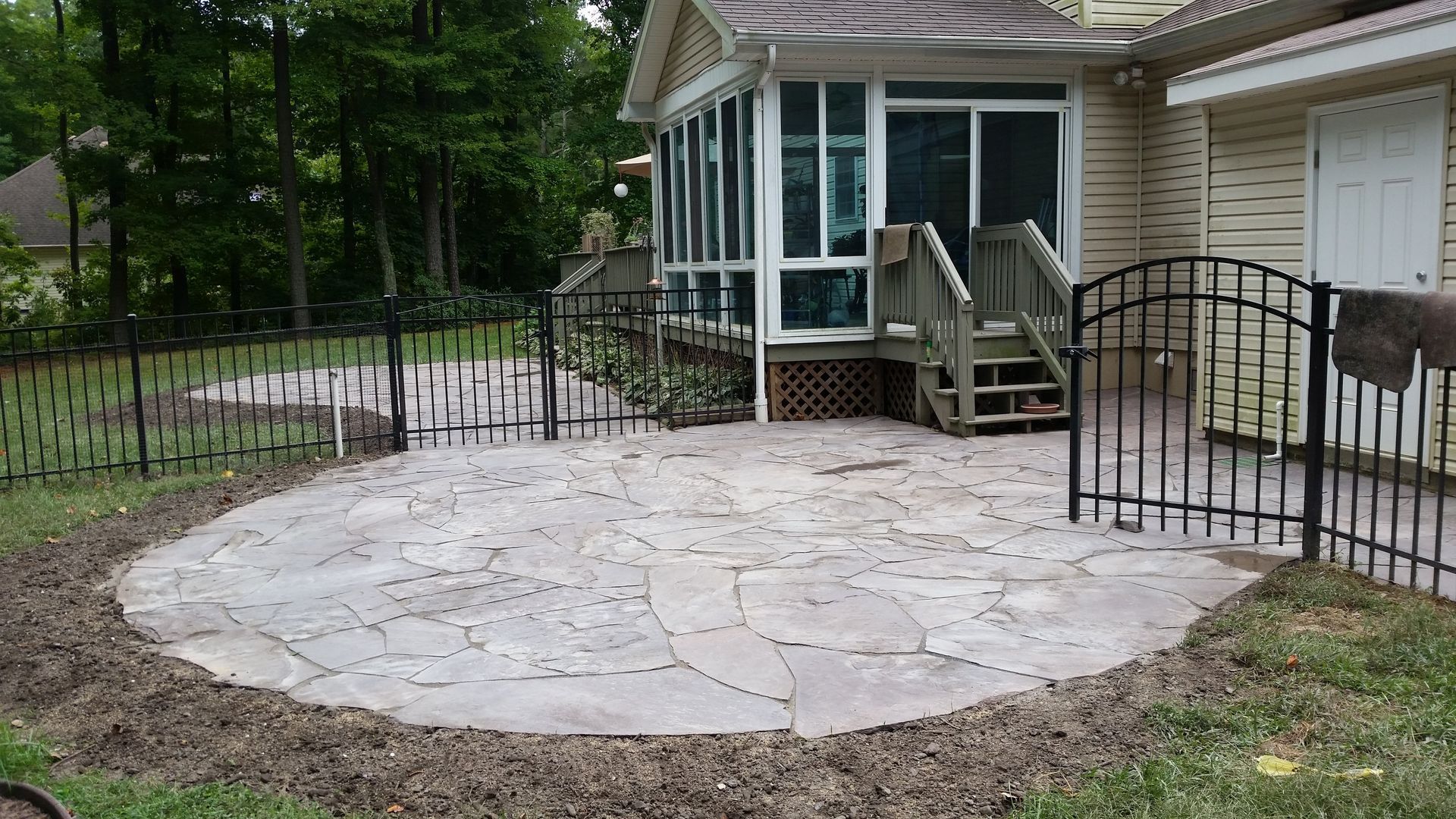 A house with a screened in porch and a patio in front of it.