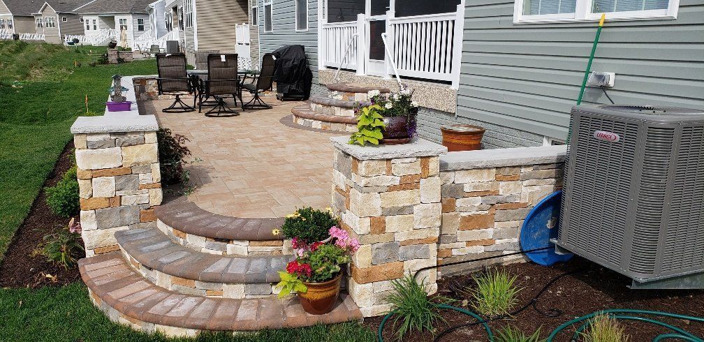 A patio with steps leading up to a screened in porch next to a house.