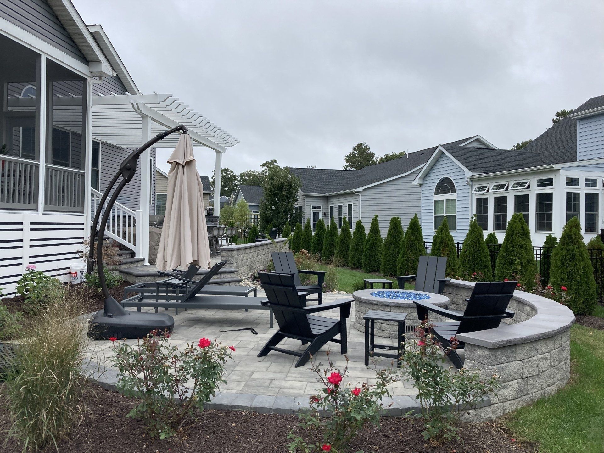 A patio with a fire pit and chairs in front of a house.