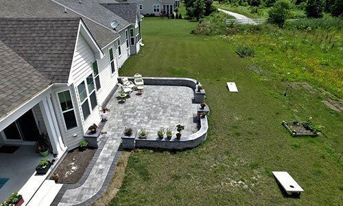 An aerial view of a house with a patio and a cornhole board in the backyard.