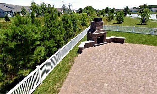 An aerial view of a backyard with a fireplace and a white fence.