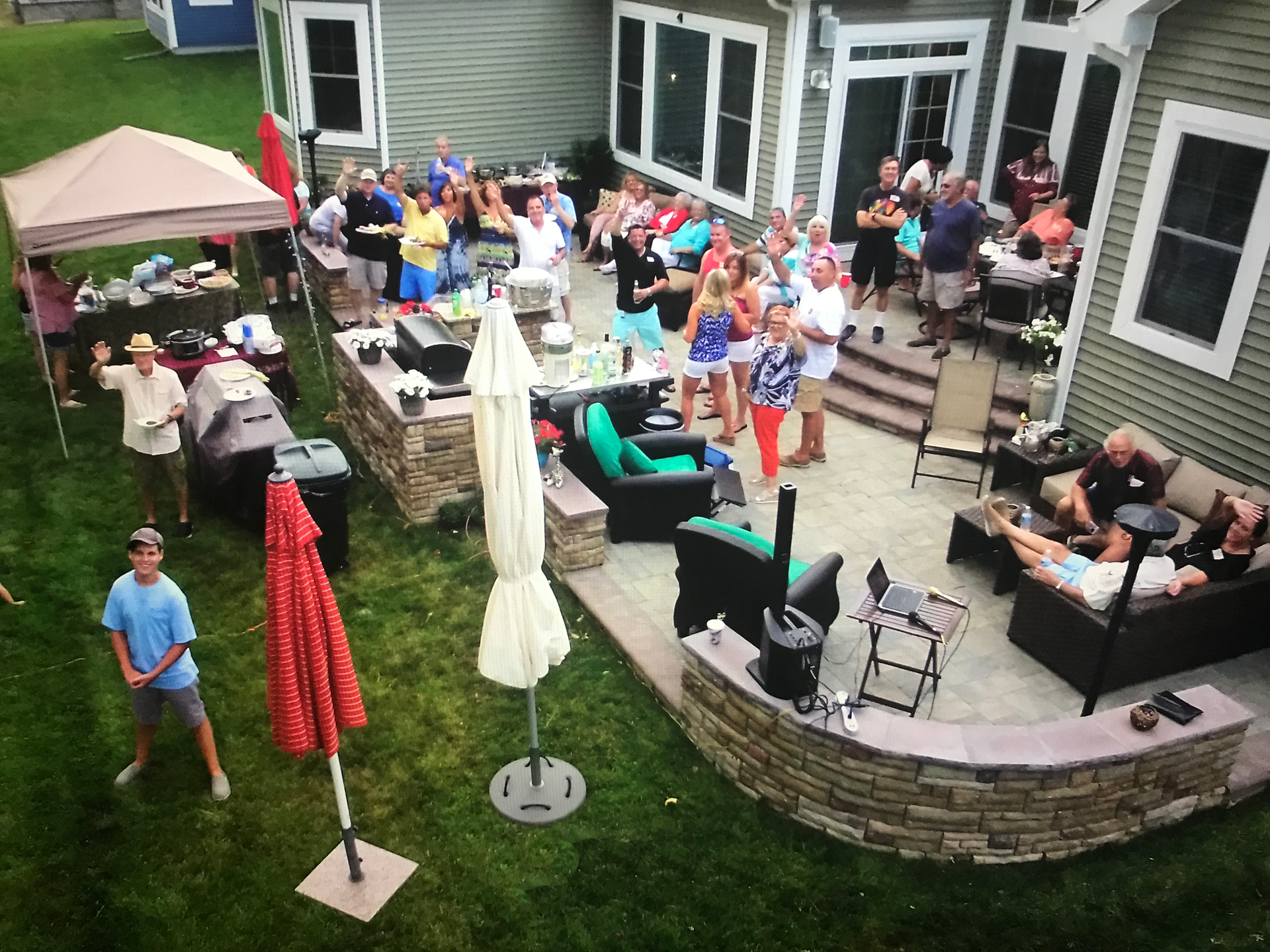 A group of people are gathered on a patio in front of a house.