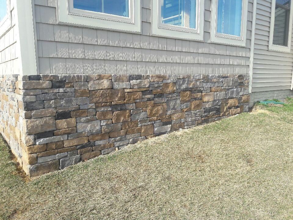 A house with a stone wall on the side of it.