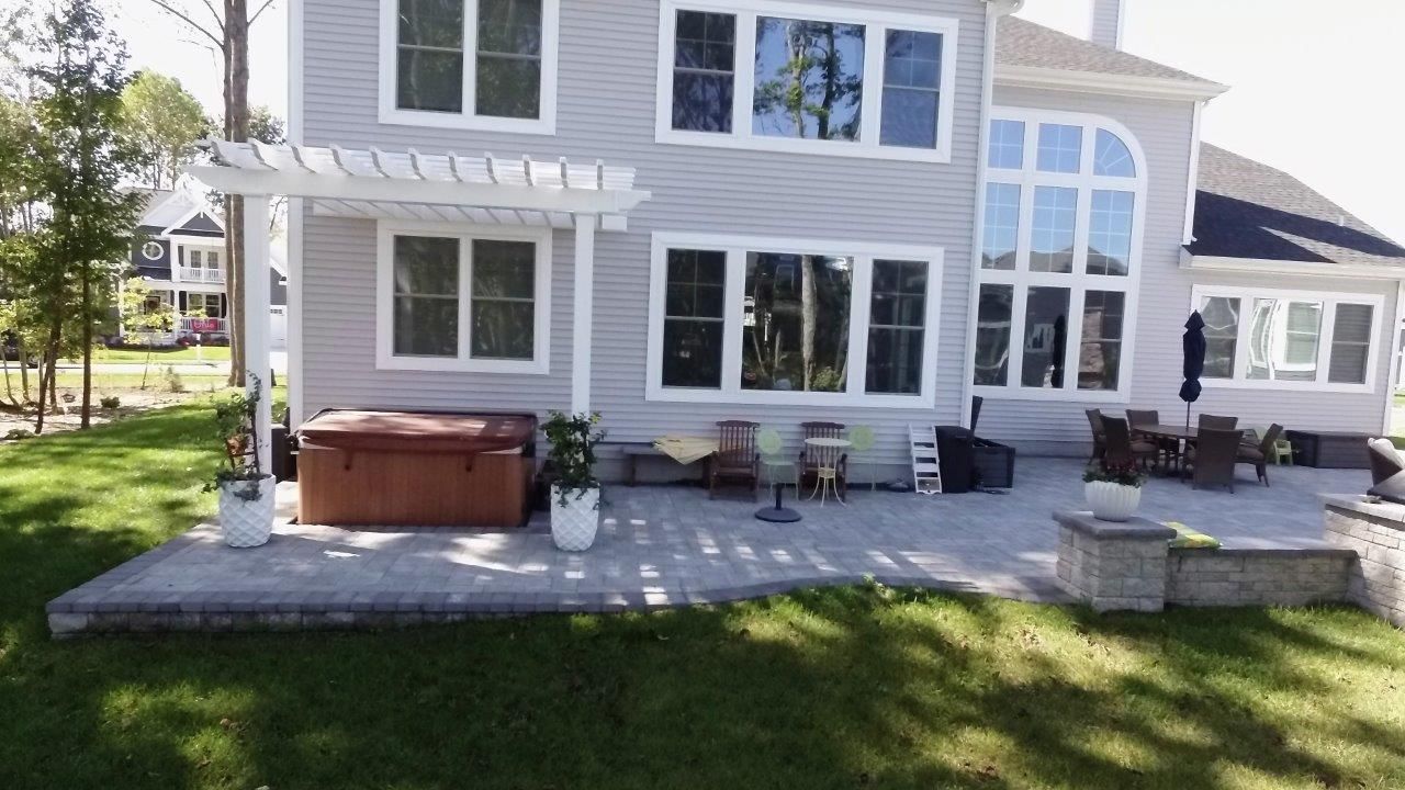 A large house with a patio and a hot tub in front of it.