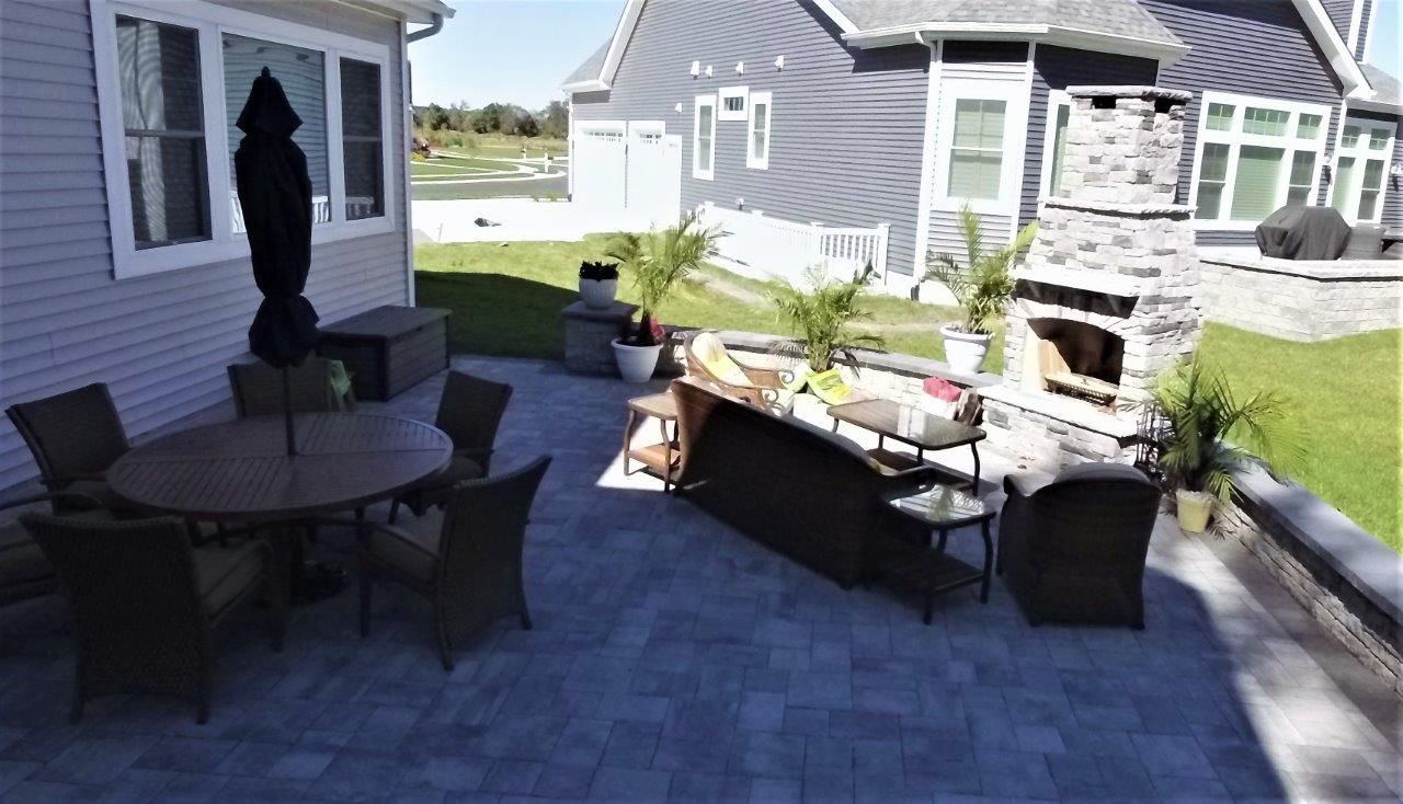 A patio with a table and chairs and a fireplace