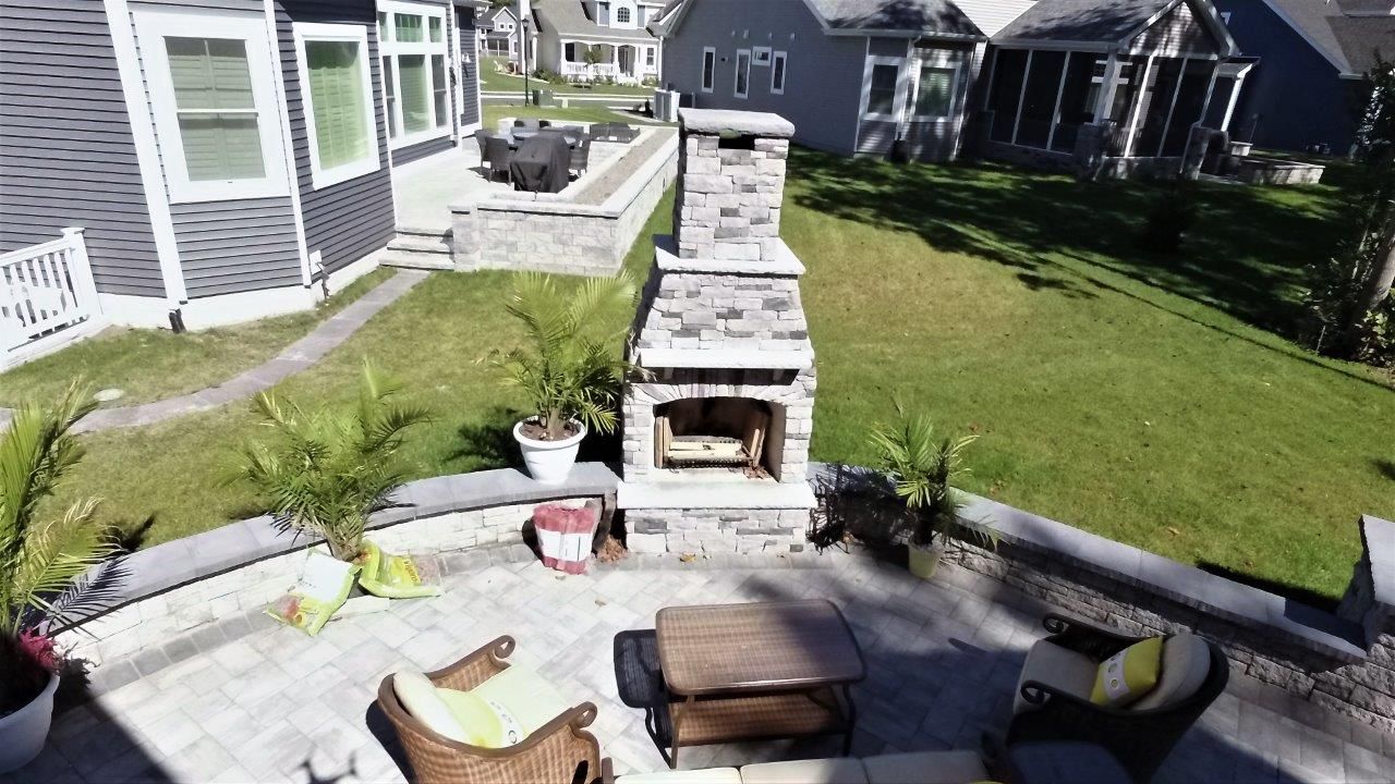 An aerial view of a patio with a fireplace and chairs in front of a house.
