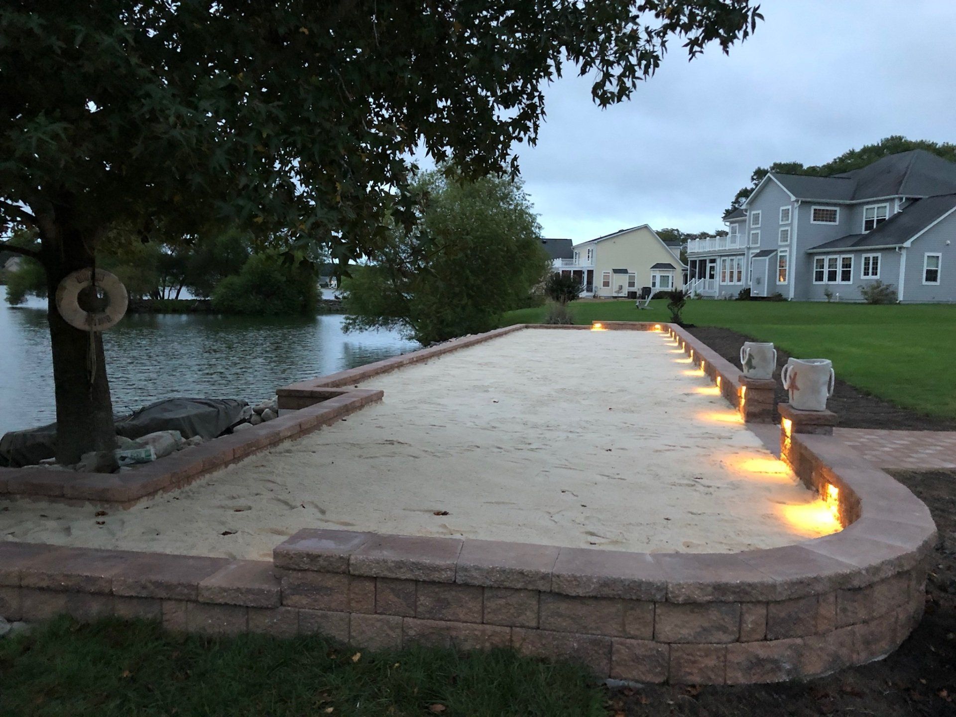 A brick walkway leading to a lake with houses in the background