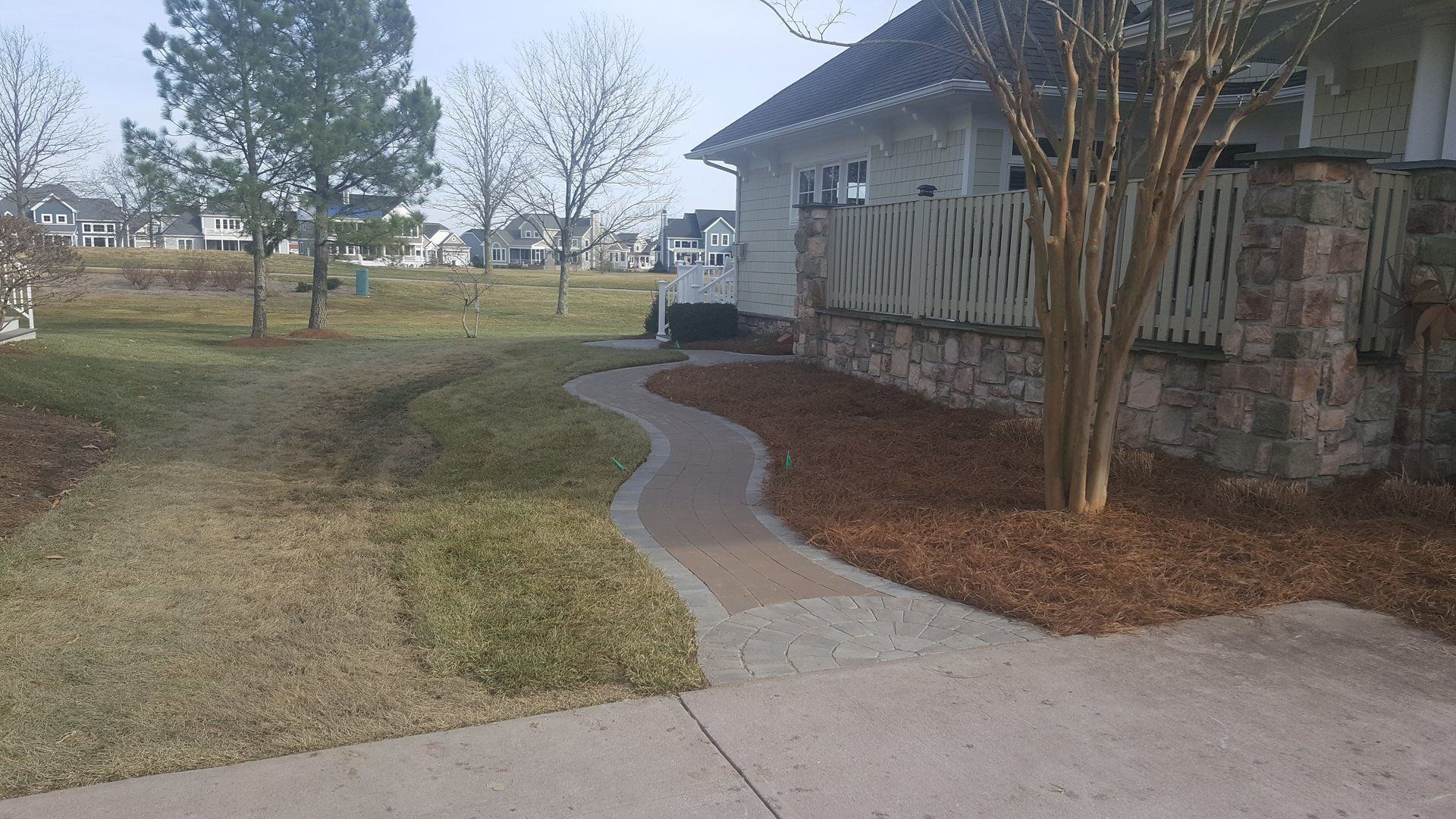 A concrete walkway leading to a house in a residential area.