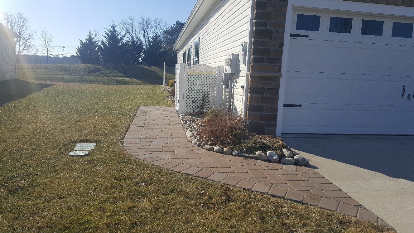 A house with a white garage door and a brick walkway leading to it.
