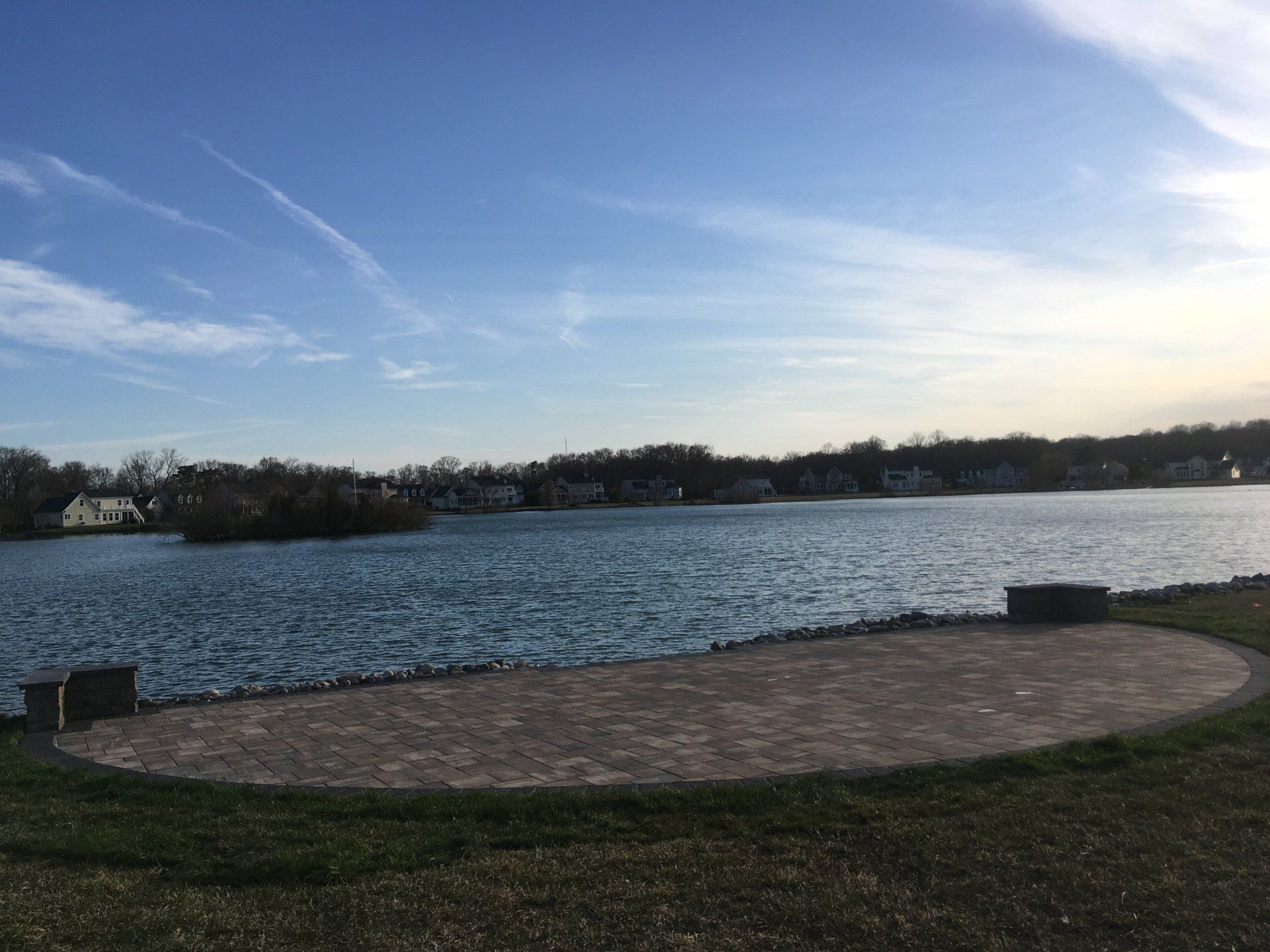 A large body of water with a brick patio in the foreground.
