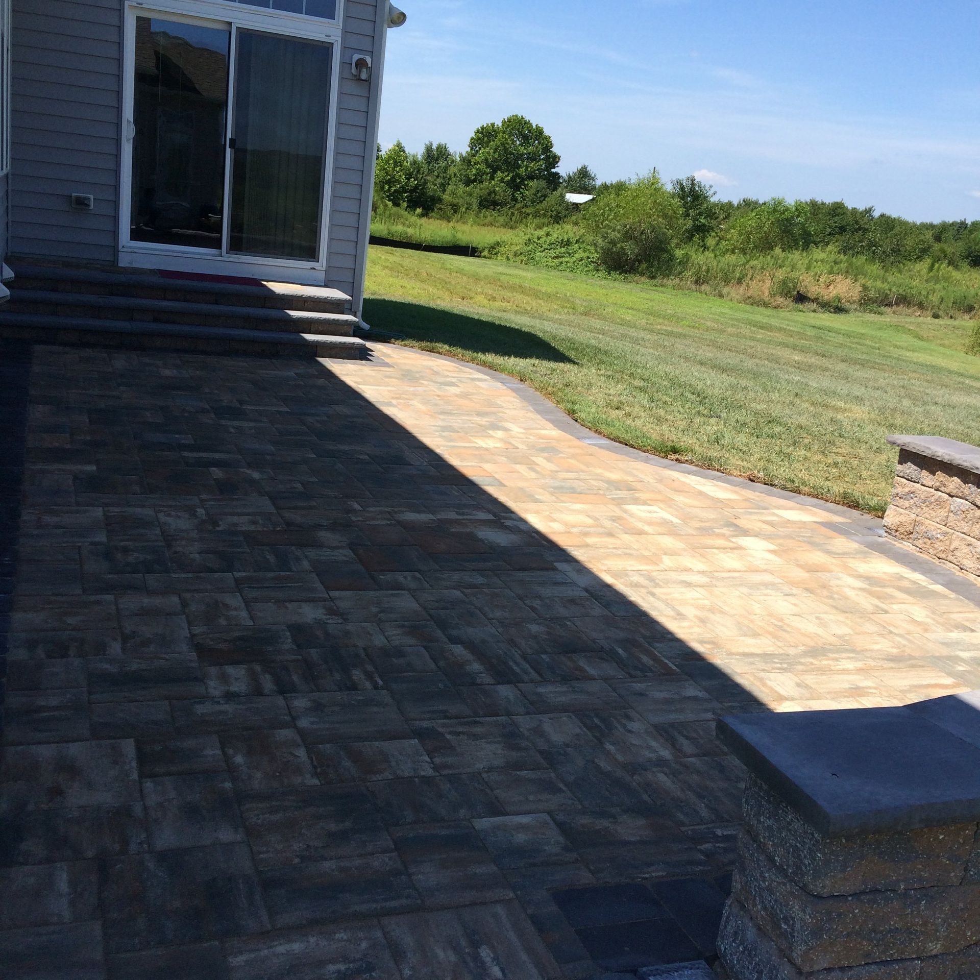 A brick walkway leading to a house with a sliding glass door