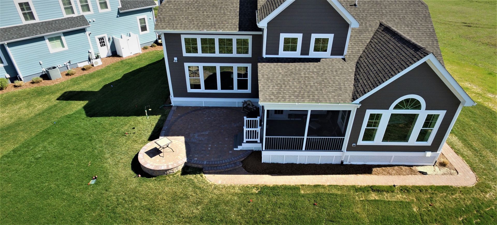 An aerial view of a large house with a patio and a fire pit.