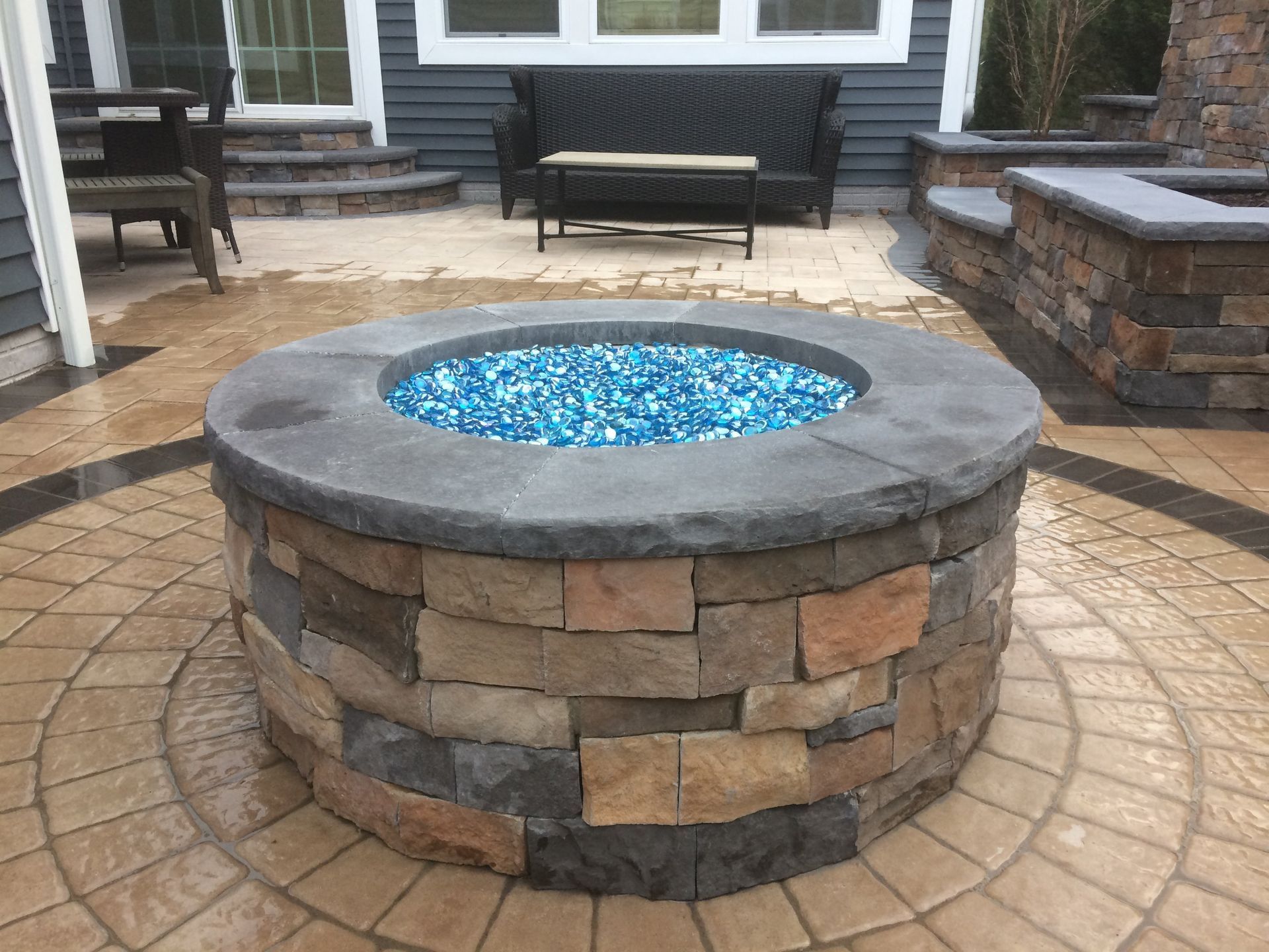 A fire pit in the middle of a patio with a couch in the background.