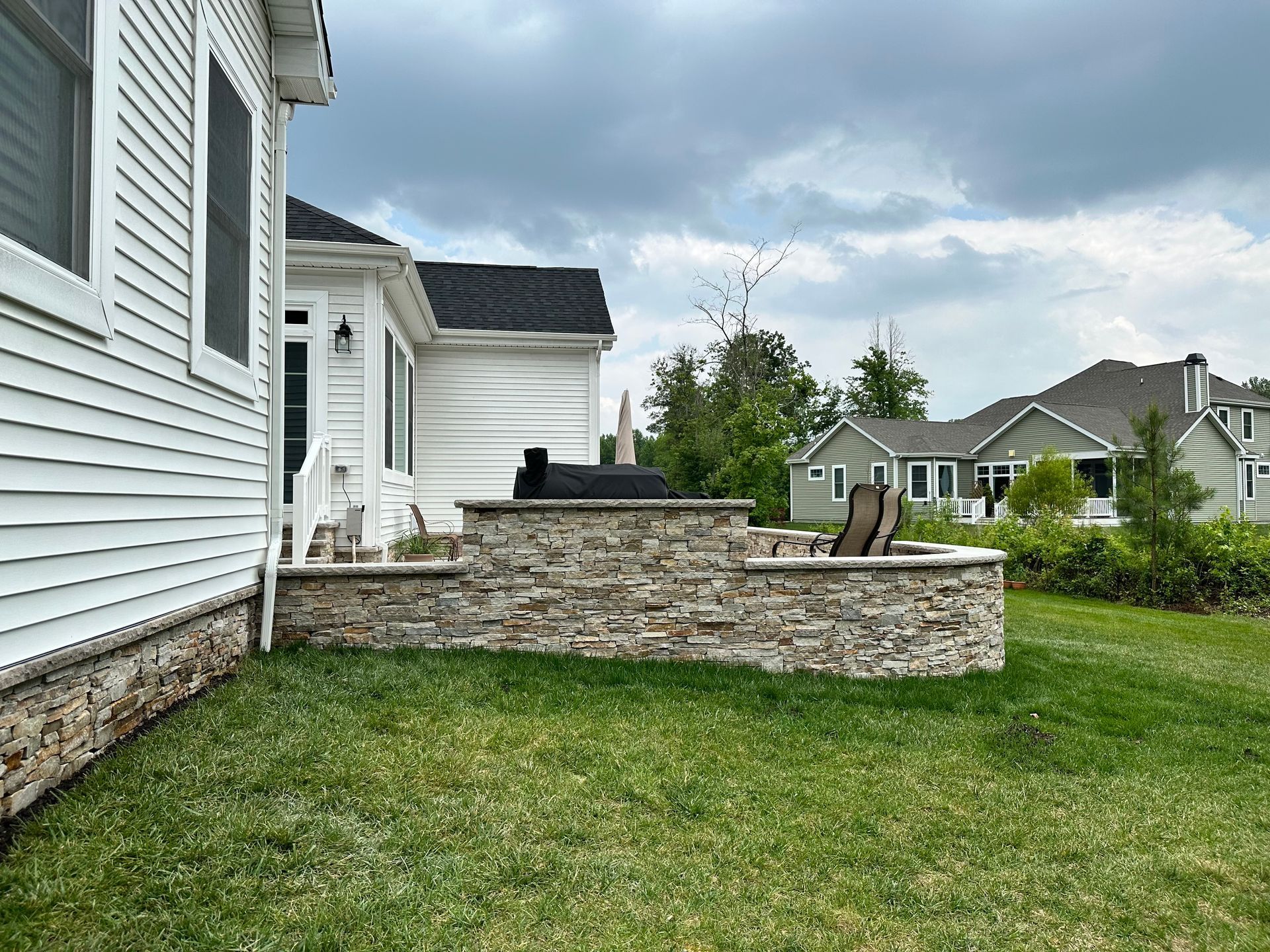 There is a stone wall in the backyard of a house.