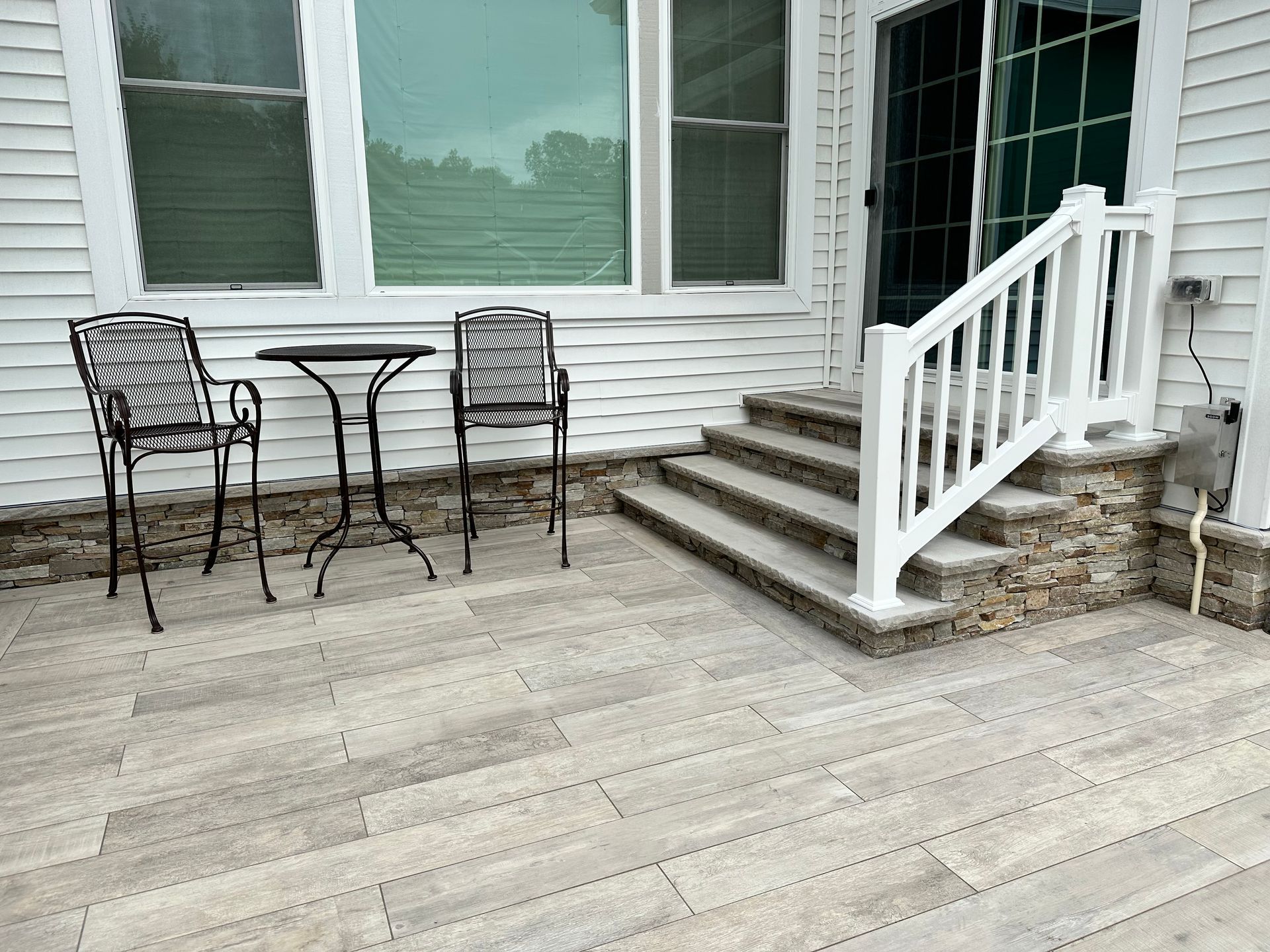 A patio with a table and chairs and stairs in front of a house.