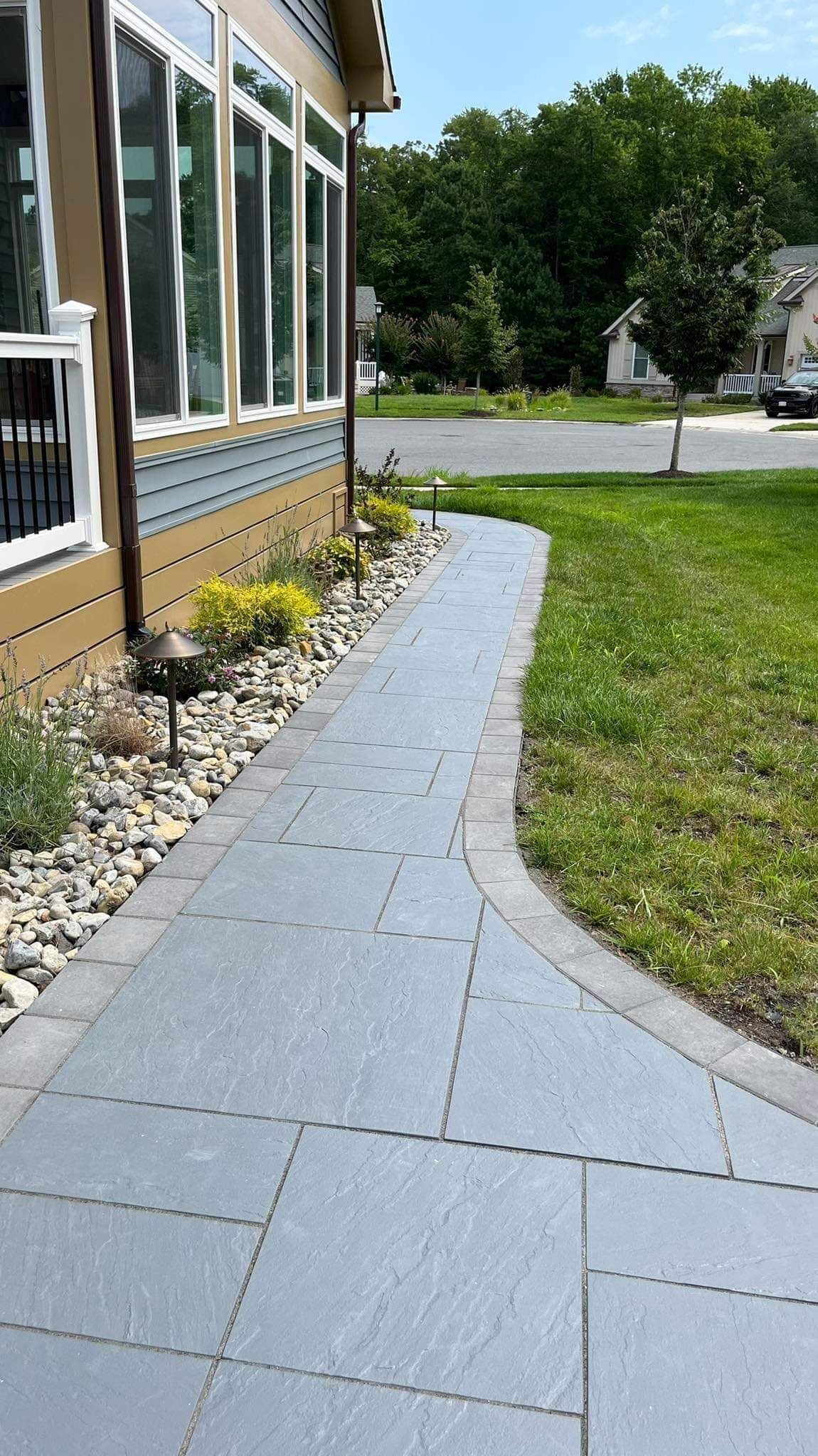 A sidewalk leading to a house with a lot of windows.