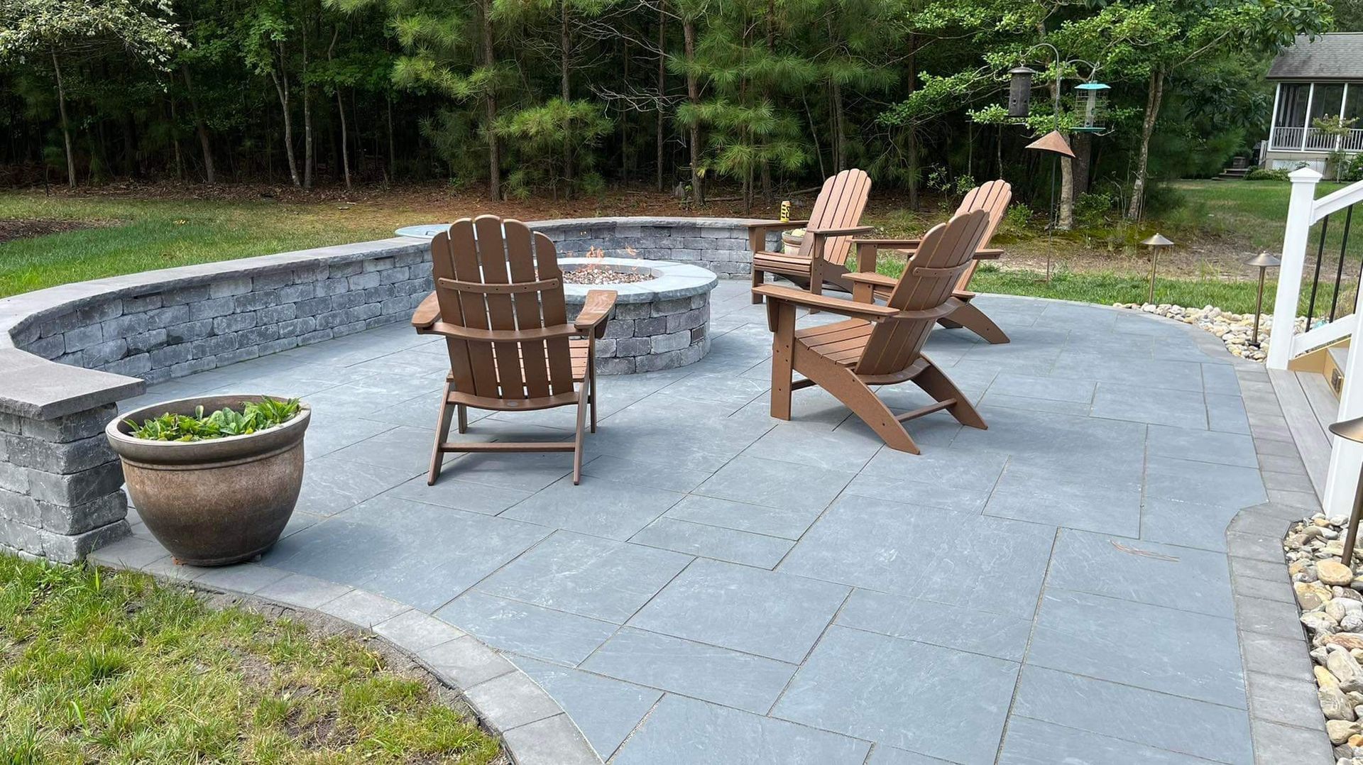 A patio with chairs and a fire pit in the backyard.