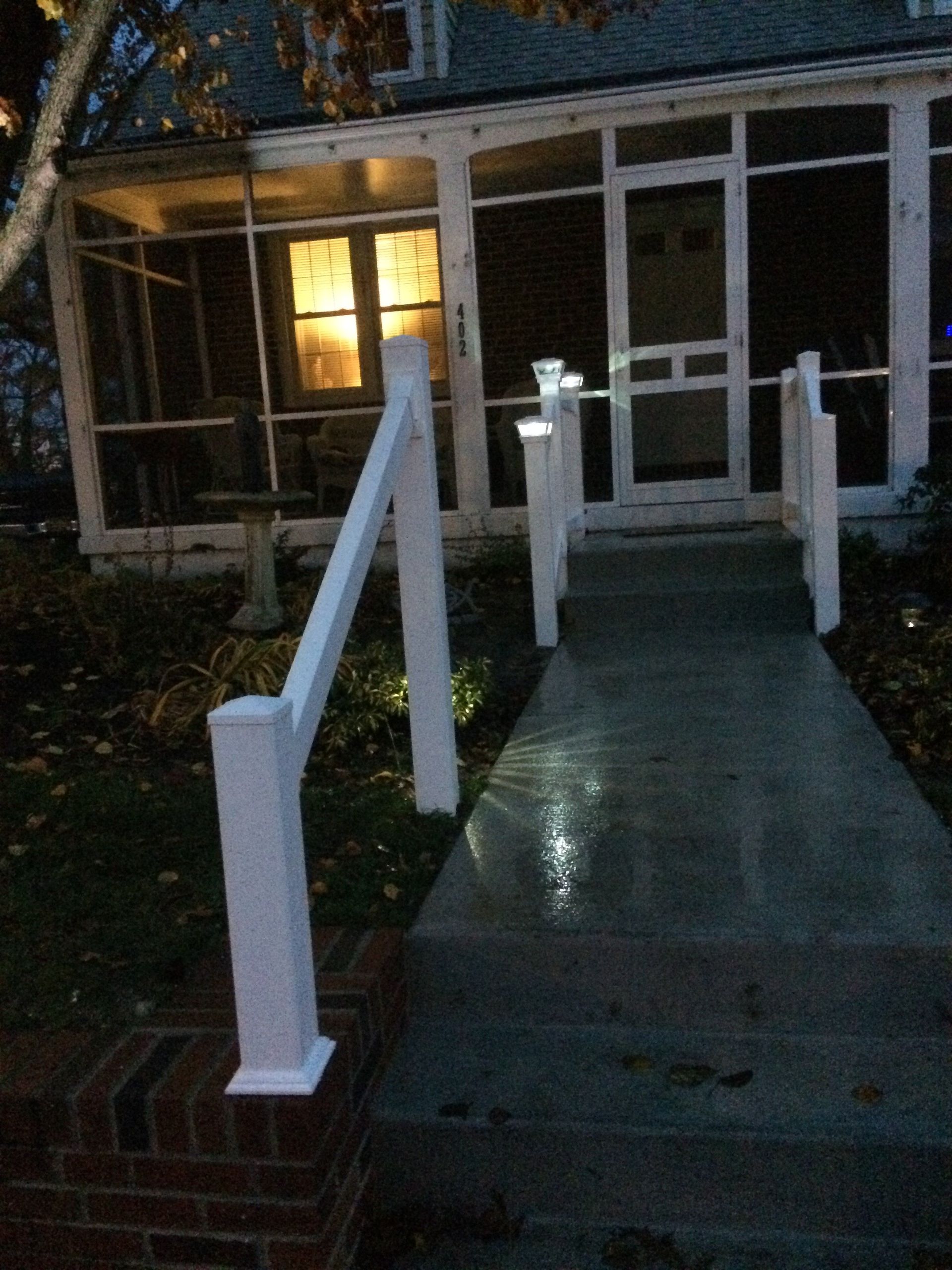 A walkway leading to a screened in porch at night