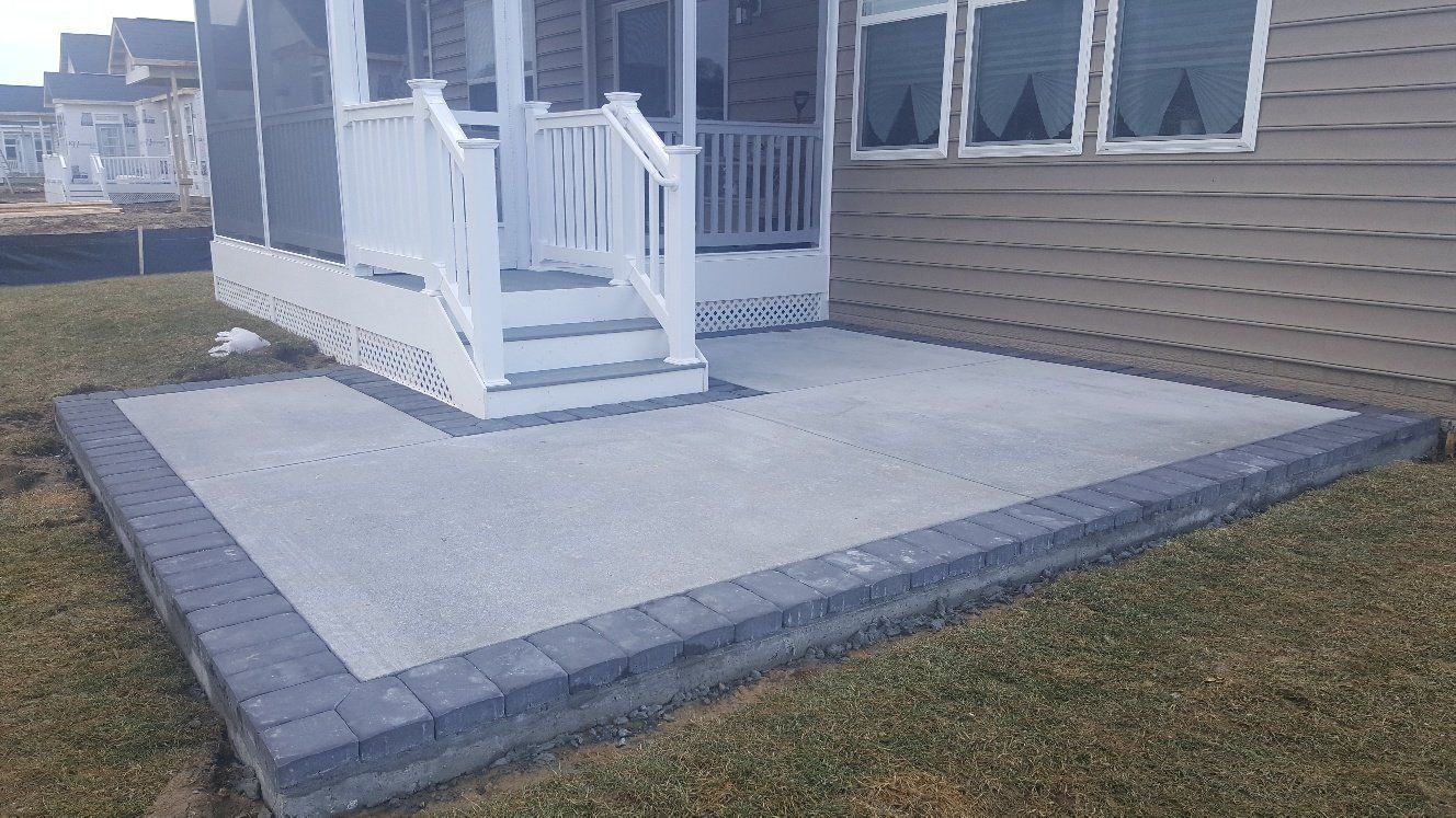 A patio with a screened in porch and stairs in front of a house.