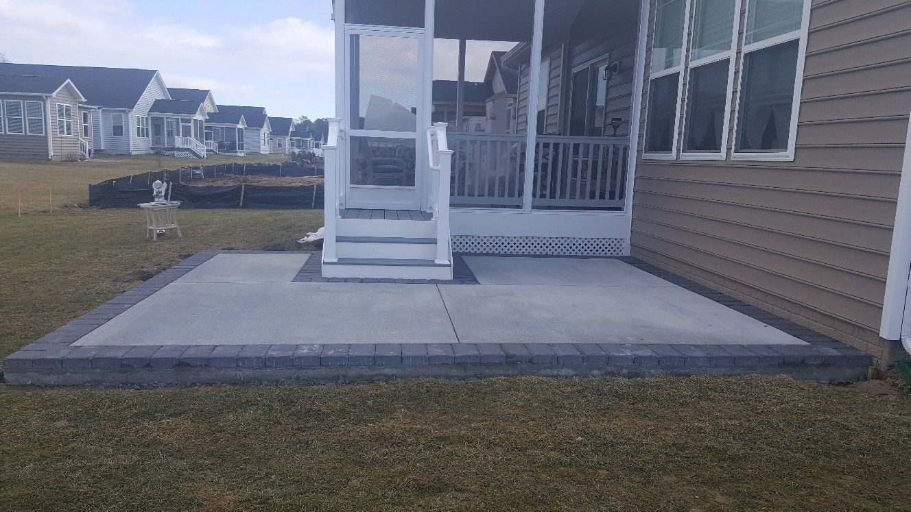 A screened in porch with a concrete patio in front of a house.