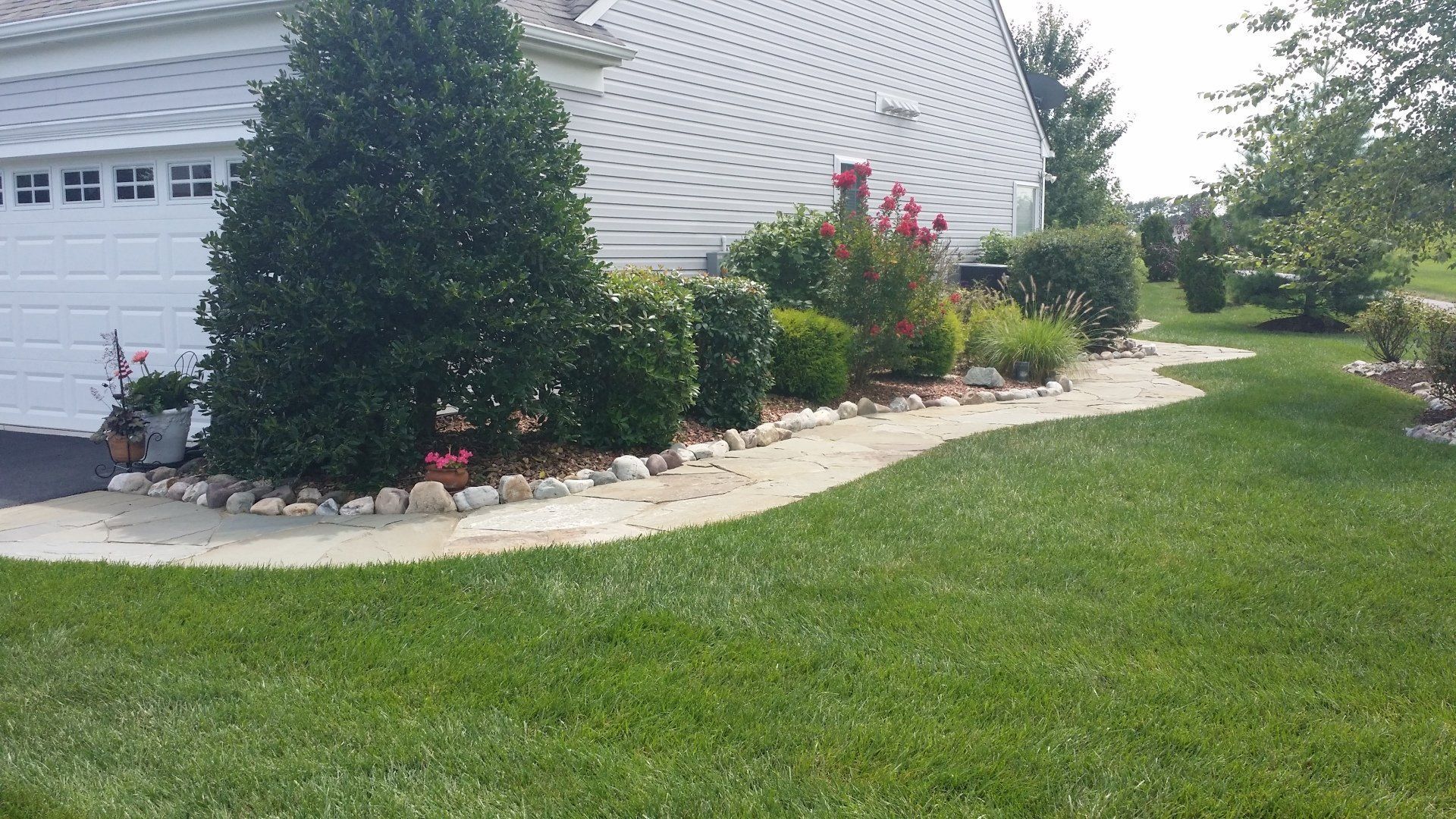 A lush green lawn in front of a white garage door
