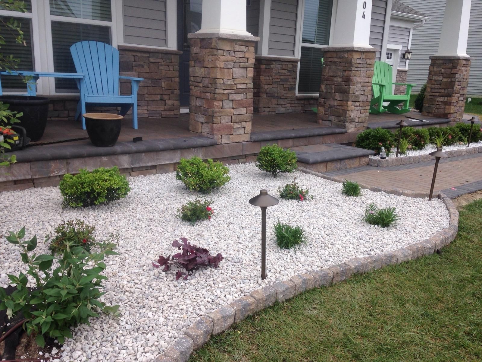 A garden with white gravel and plants in front of a house.