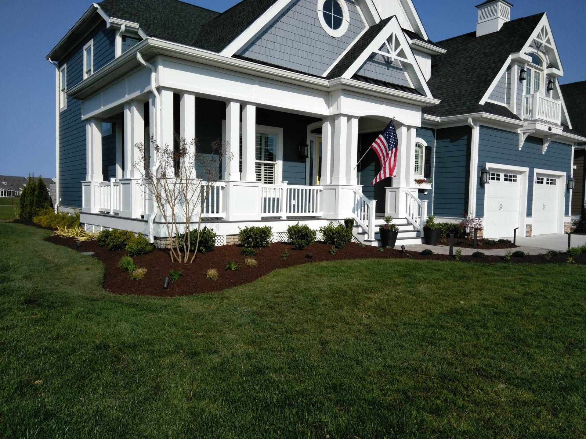 A blue and white house with an american flag on the porch
