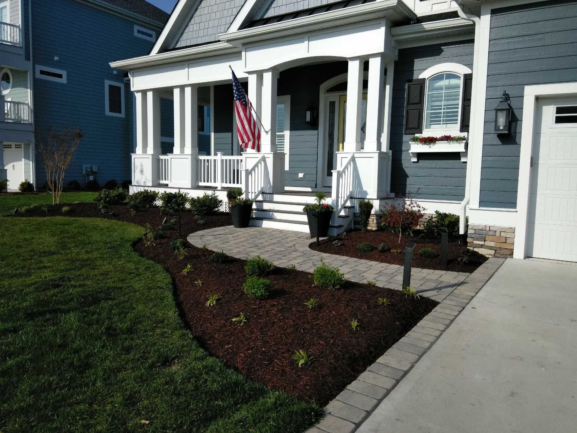 A blue house with a white porch and an american flag