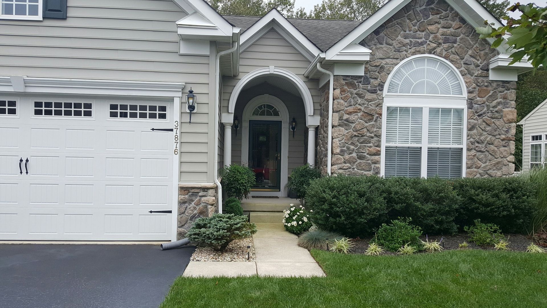 A house with a white garage door and a walkway leading to the front door.
