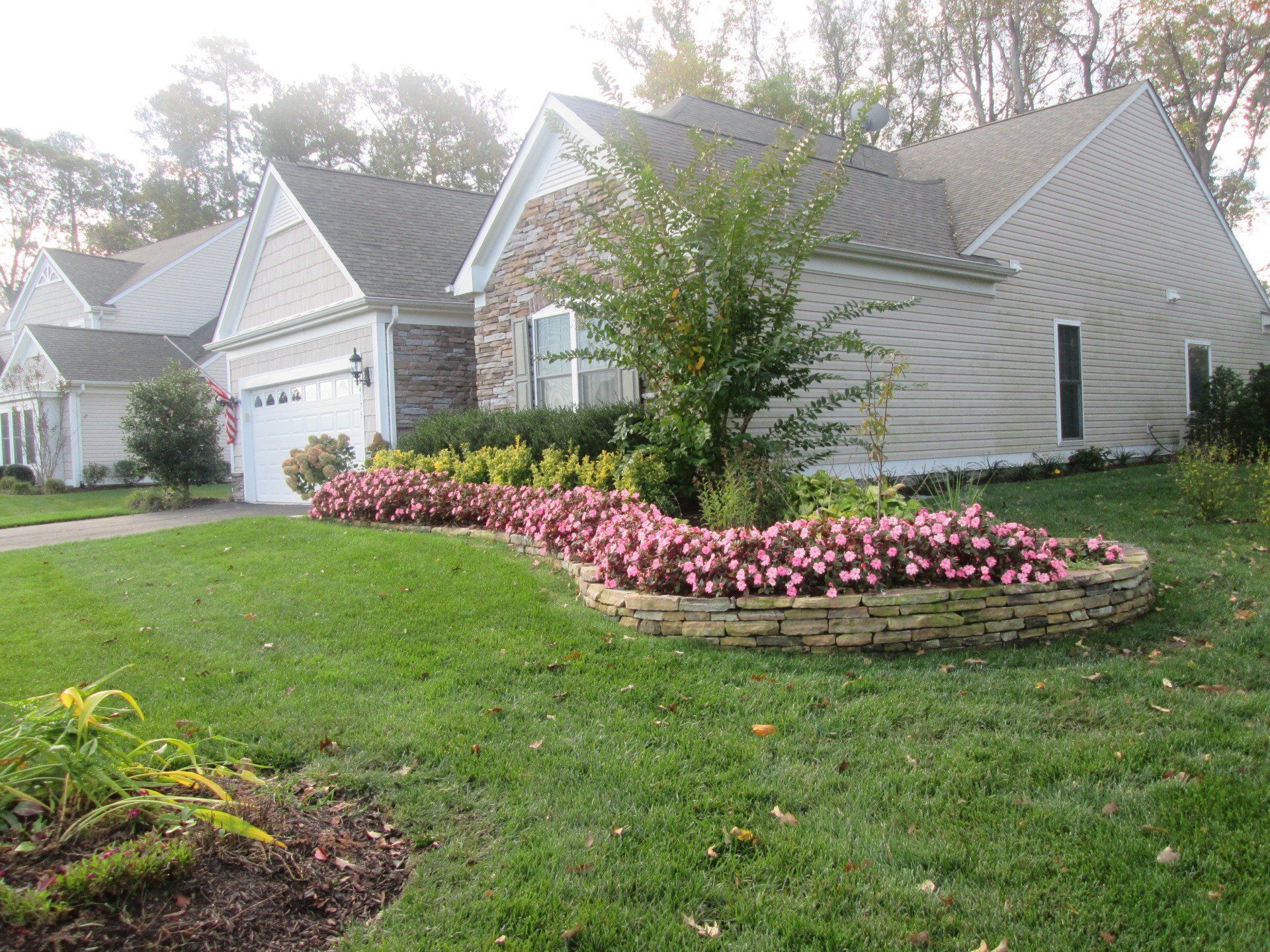 A house with a lush green lawn and flowers in front of it