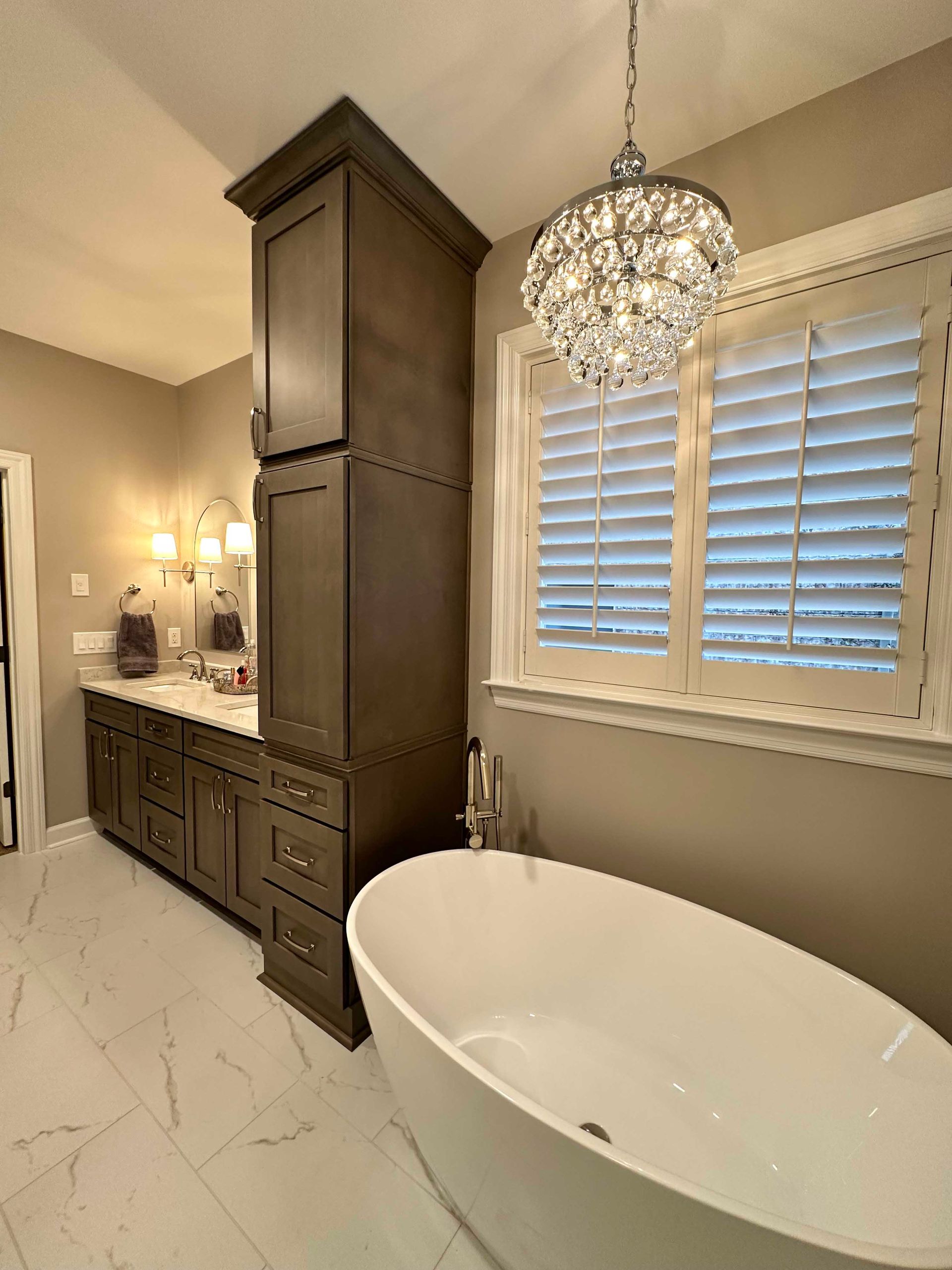 Elegant bathroom with a free-standing tub, dark cabinets, and a crystal chandelier.