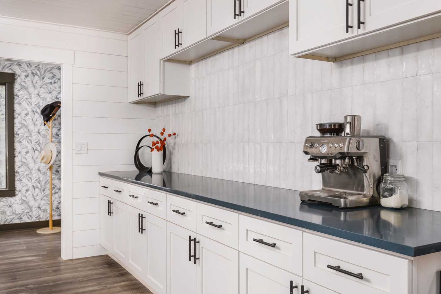 White kitchen cabinets with dark countertop, stainless steel espresso machine.