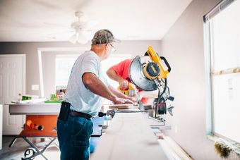 Two men are working on a circular saw in a room.