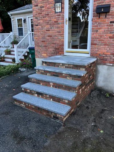 A set of stairs leading up to the front door of a brick house.