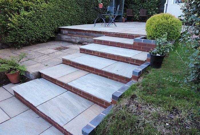 A set of stairs leading up to a patio with a table and chairs.