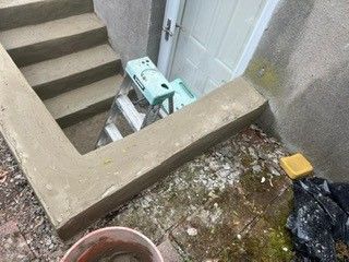 A ladder is sitting on the side of a concrete staircase next to a door.