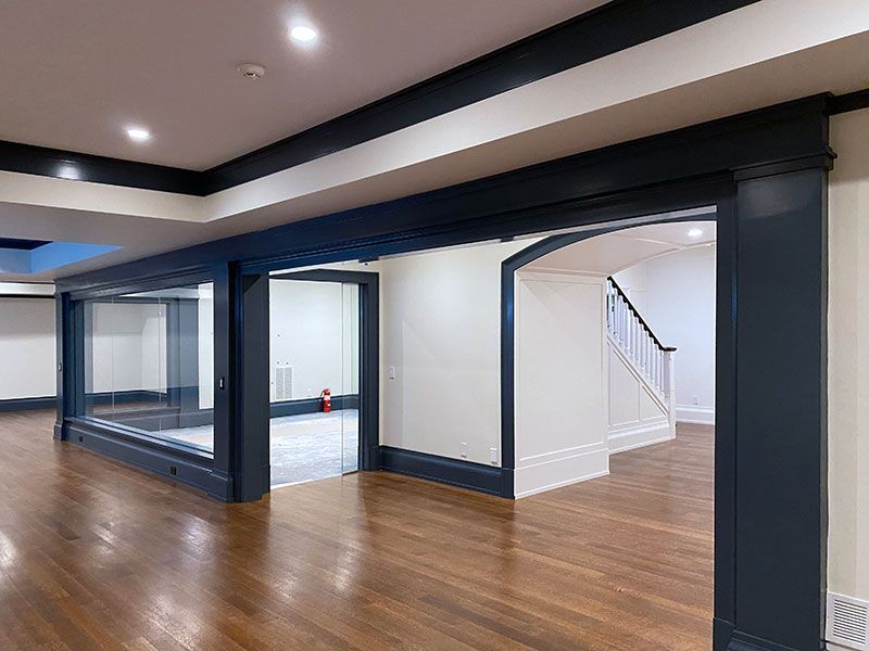 An empty basement with hardwood floors and a staircase.
