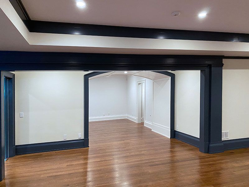 An empty basement with hardwood floors and white walls.