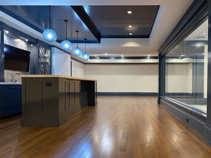 An empty room with hardwood floors and a large island in the middle