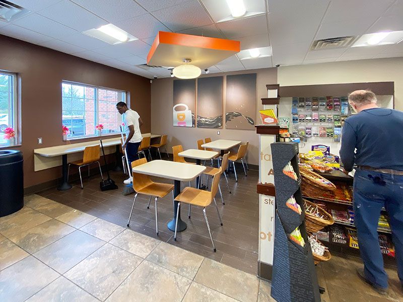 A man is cleaning tables and chairs in a restaurant.