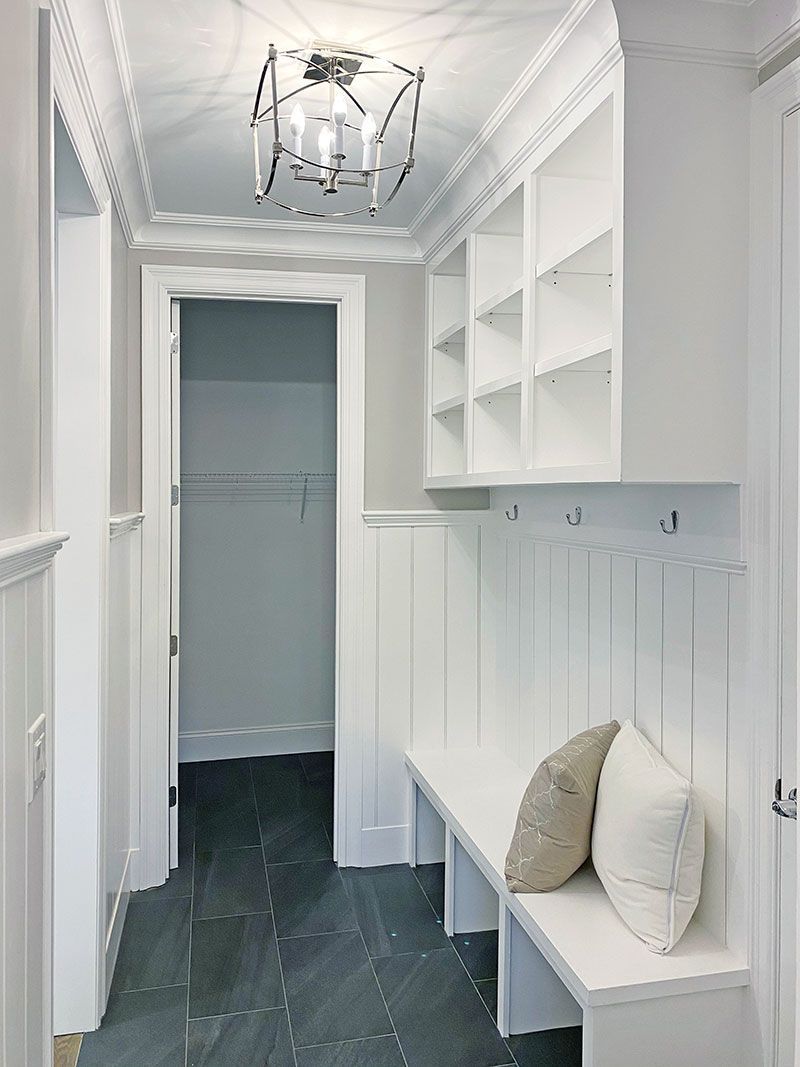 A hallway with a bench and shelves in a house.
