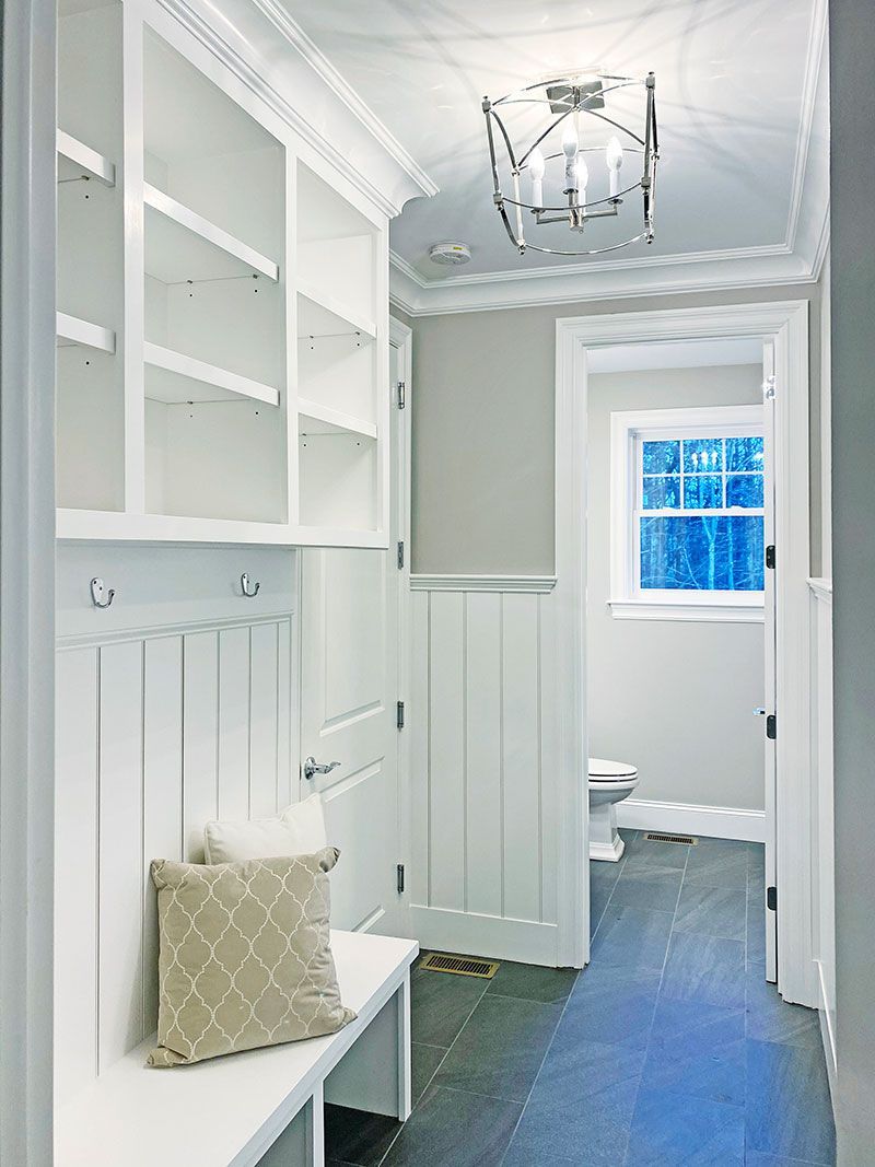 A hallway with white cabinets and a pillow on a bench