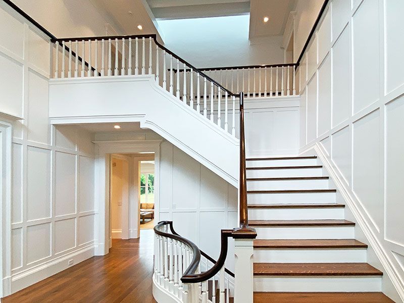 A white staircase with wooden steps and a black railing
