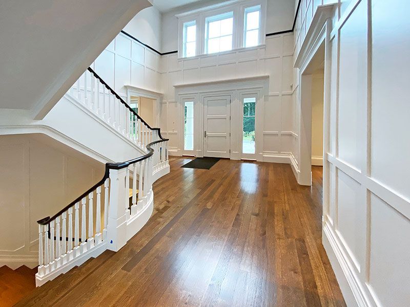 An empty hallway with a staircase and wooden floors
